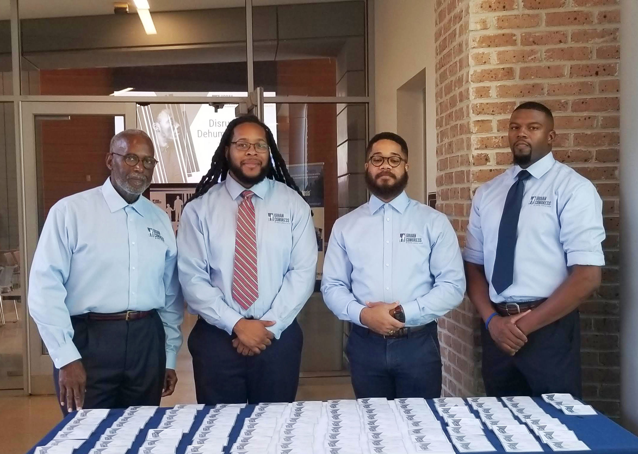 Photo of four black men standing together behind a table.