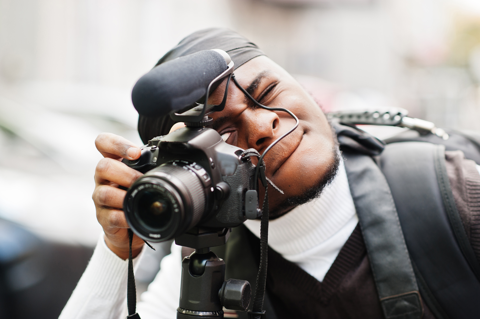 A black man with a professional camera and microphone.